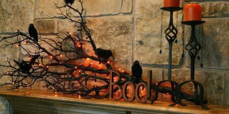 Crows on a branch with glowing orange lights on a mantle as Halloween decorations